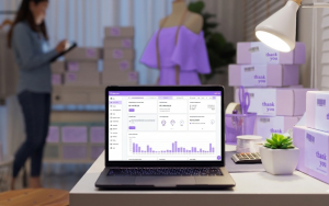 Notebook aberto exibindo o dashboard de vendas da Appmax, o melhor gateway para Shopify, em um ambiente de e-commerce com pacotes de entrega e manequim